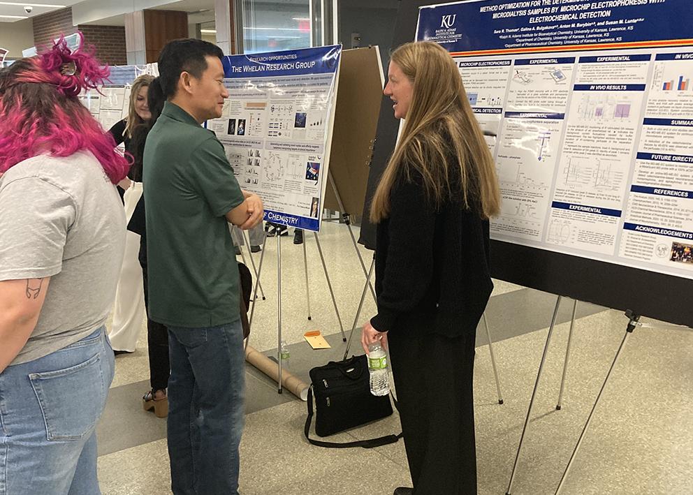 student presenting poster to faculty member